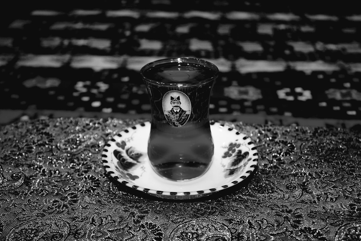 A decorative Persian tea glass with saucer resting on a patterned textile